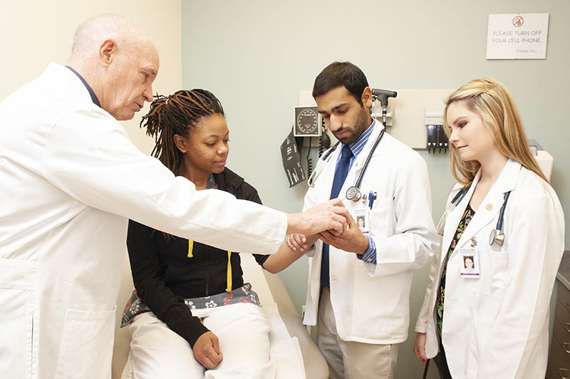 Dr Atkinson instructs students Sagar Mehta and Lyndsey Cole. Patient at Clinic on Manchester  Latasha Brown